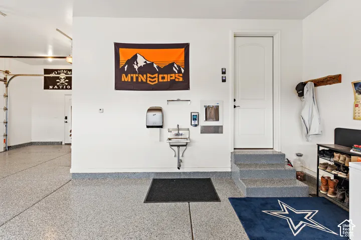Garage with an epoxy floor finish, utility sink, and a built-in water dispenser