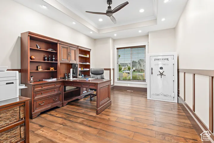 Wood-finish flooring with a tray ceiling and recessed lighting