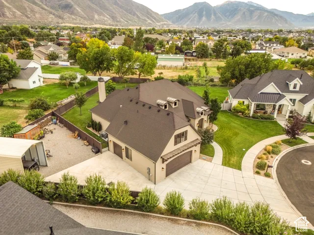 Mountain backdrop, large lot, paved driveway, attached garage, and mature landscaping