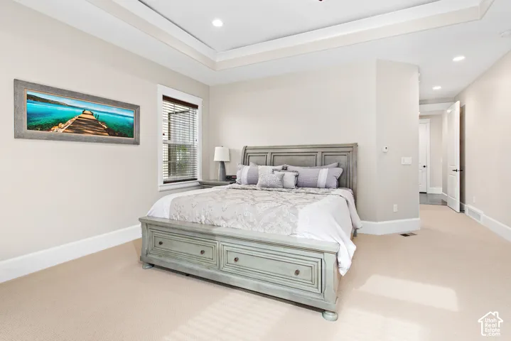 Tray ceiling with recessed lighting, light neutral-toned walls, wall-to-wall carpeting, and a window with blinds