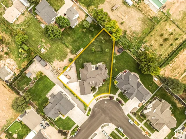 Aerial view highlighting a cul-de-sac street, surrounding residences, and a substantial lot with mature trees