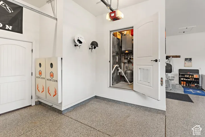 Garage with speckled epoxy flooring, white paneled doors, and a utility closet