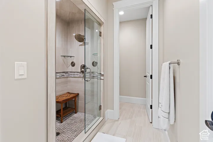 Glass-enclosed shower with a tiled surround, mosaic accent band, and a patterned tile floor