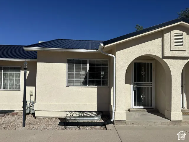 Stucco exterior with arched entry, dark metal roof, and covered porch