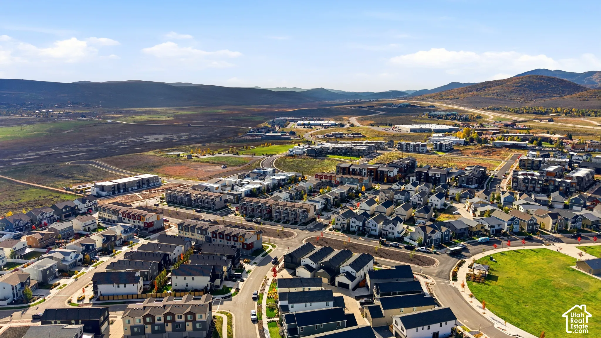Expansive residential development featuring a mix of detached homes and townhomes, surrounded by natural land