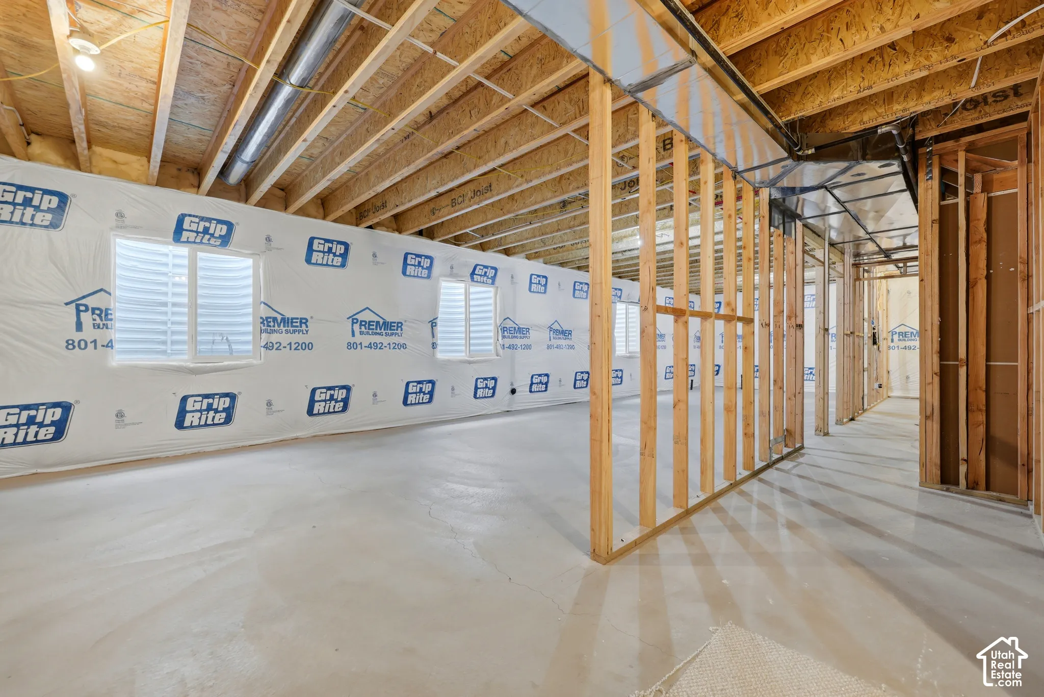 Unfinished basement space featuring exposed wood framing, concrete flooring, and multiple egress windows