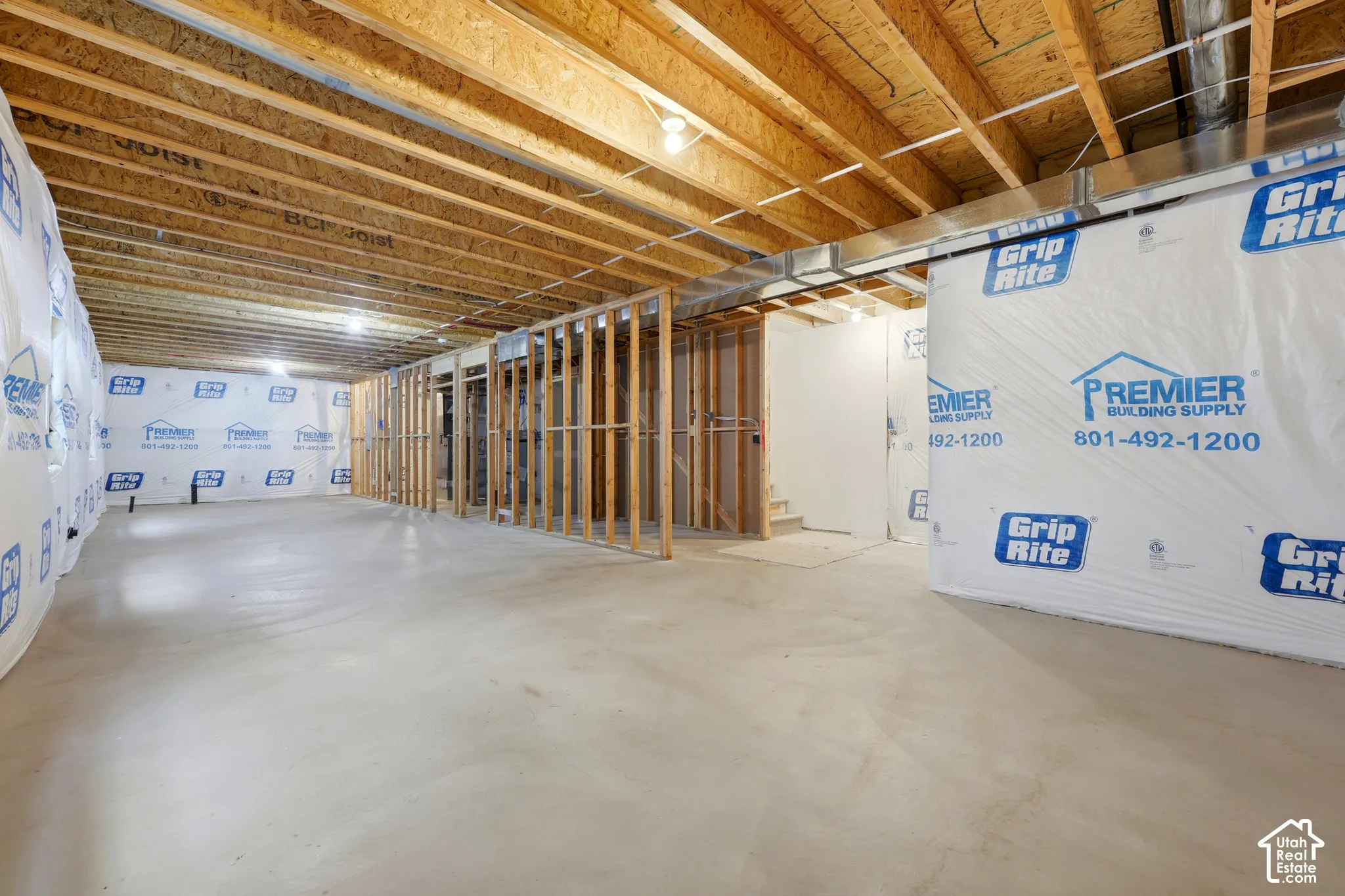 Unfinished basement with exposed wood joists, concrete flooring, and partial wood framing
