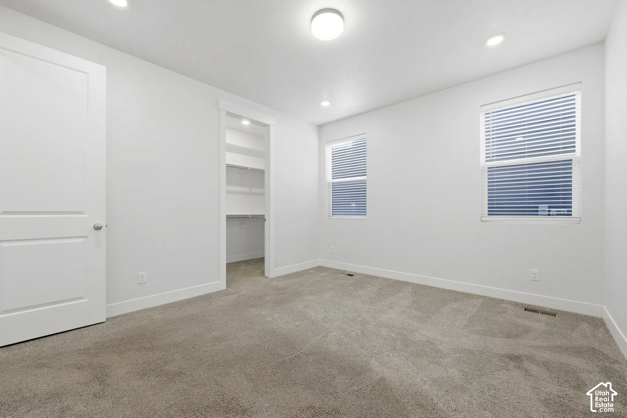 Recessed lighting, flush mount lighting, two windows with blinds, built-in closet shelving, and light-toned carpeting