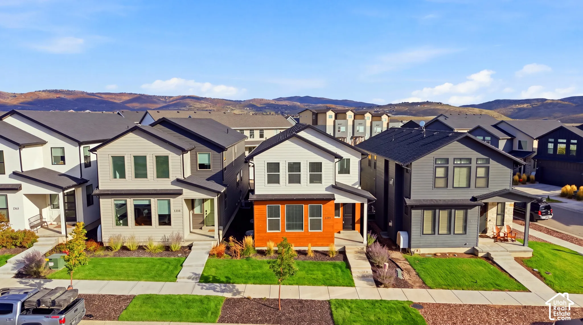 Modern construction featuring a dark shingle roof, light gray siding, and a covered porch