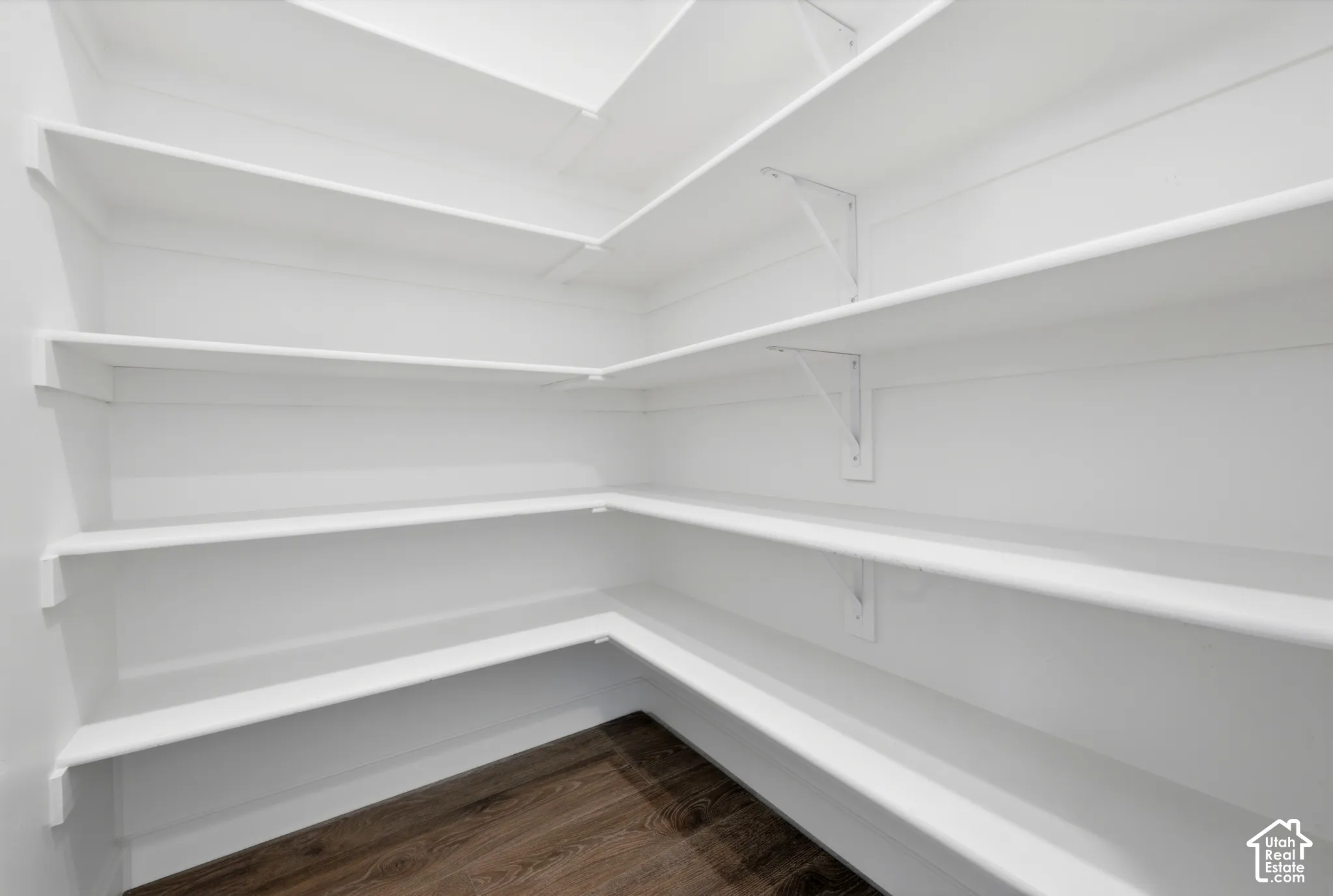 Custom shelving system with multiple white shelves and wood-finish flooring