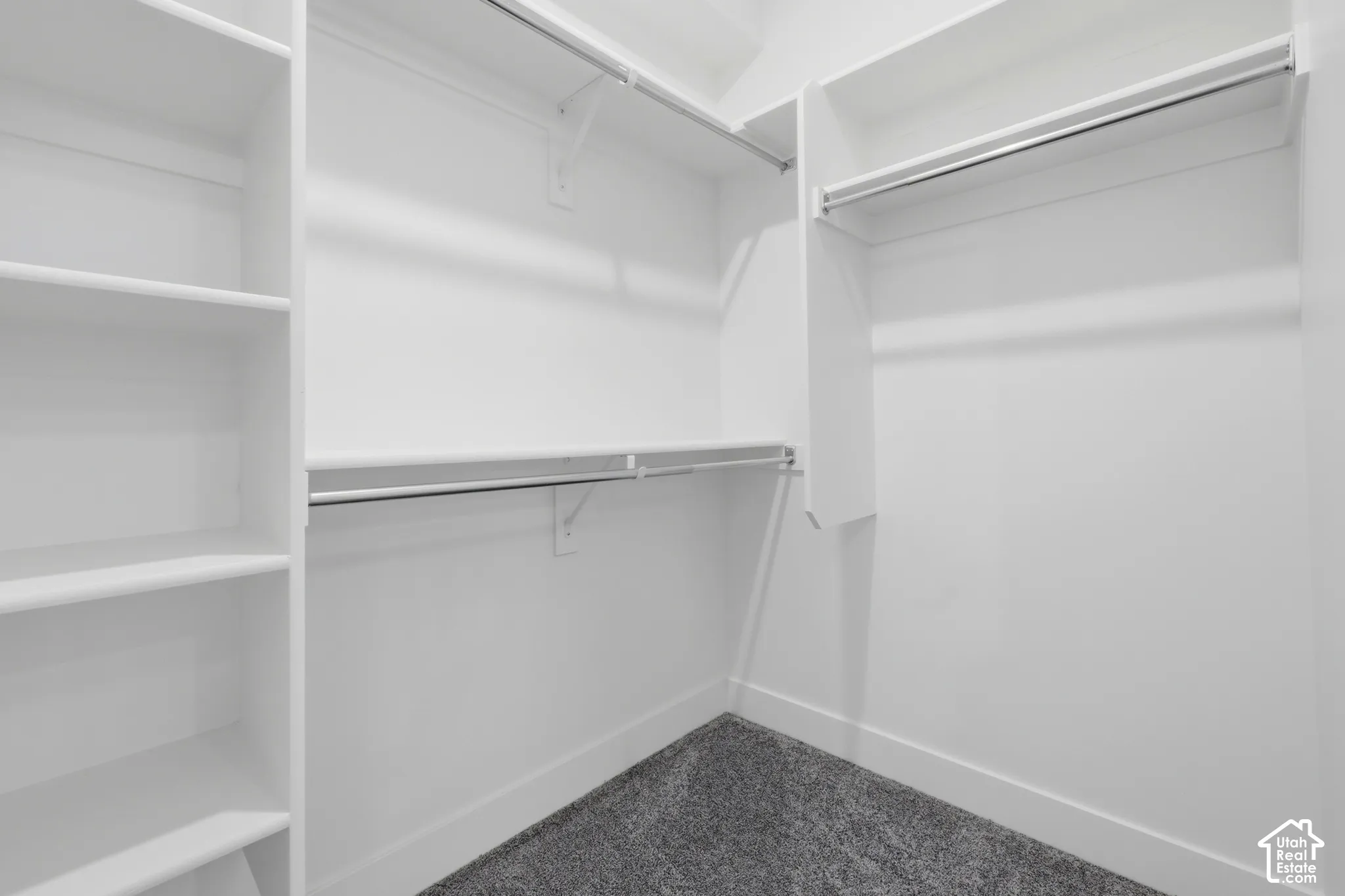 Walk-in closet with built-in shelving, multiple hanging rods, and gray carpet