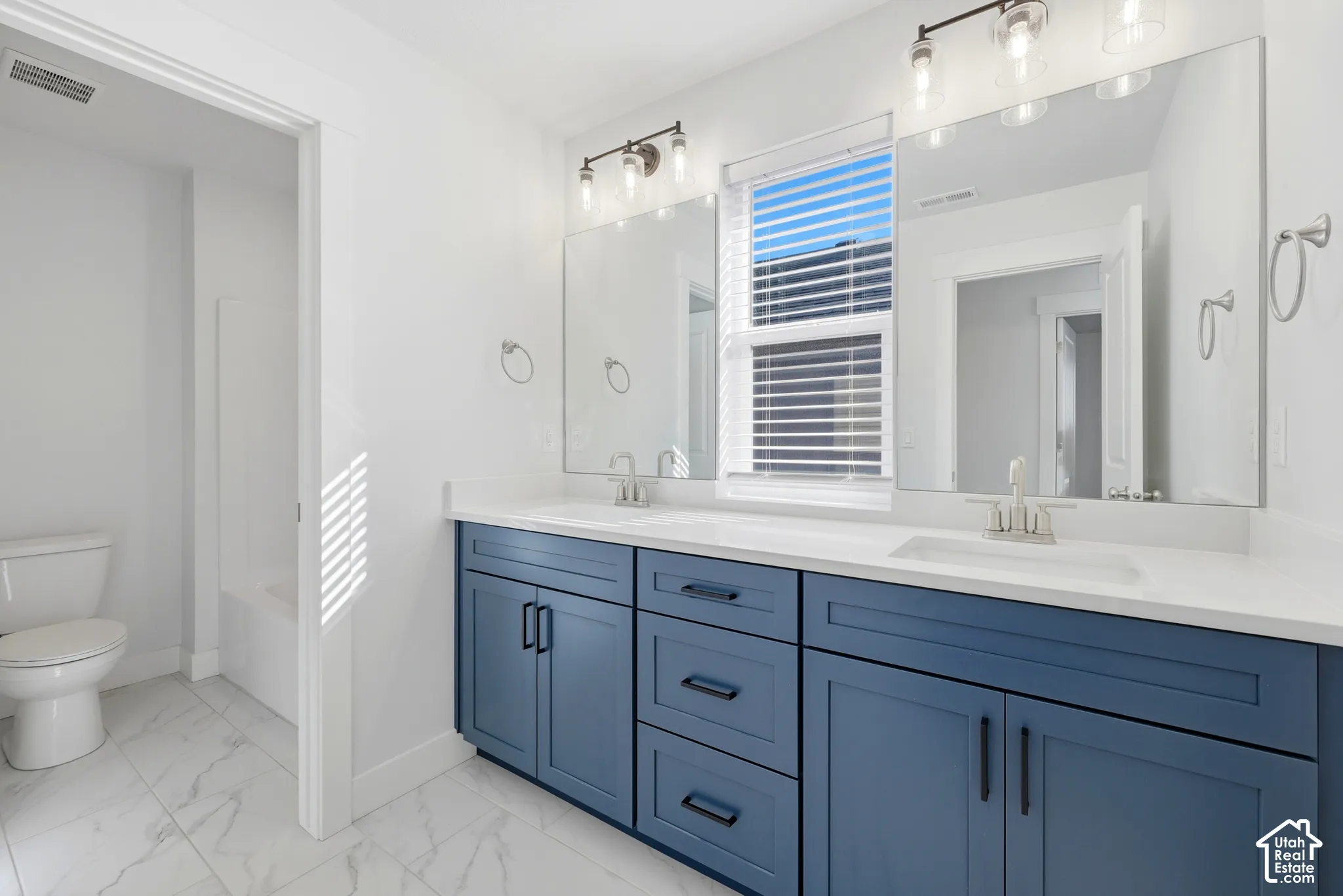 Dual vanity with a white countertop and integrated sinks, blue shaker-style cabinetry, and brushed nickel hardware
