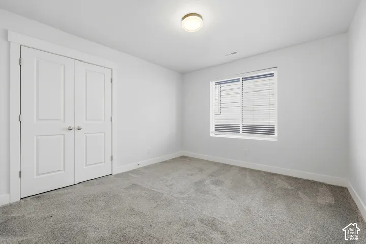 Neutral wall color, gray carpet, white trim, double panel doors, and a window with blinds