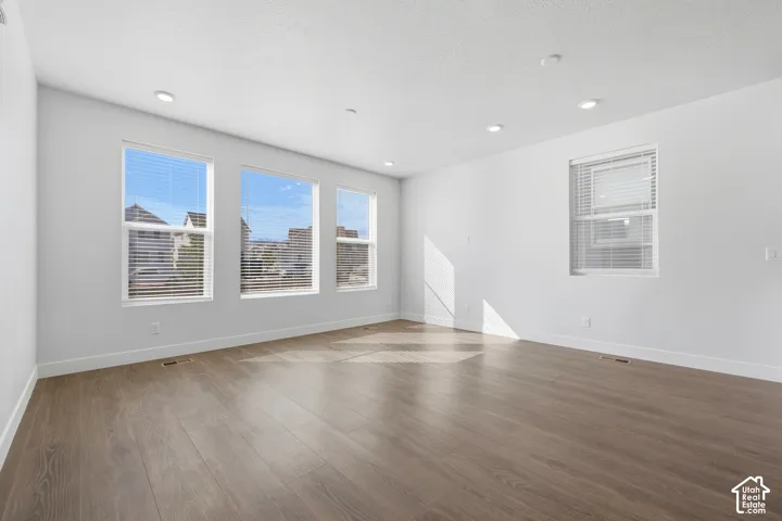Wood-finish flooring, white walls, multiple windows, recessed lighting, and window blinds