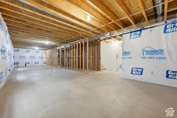 Unfinished basement with exposed wood joists, concrete flooring, and partial wood framing