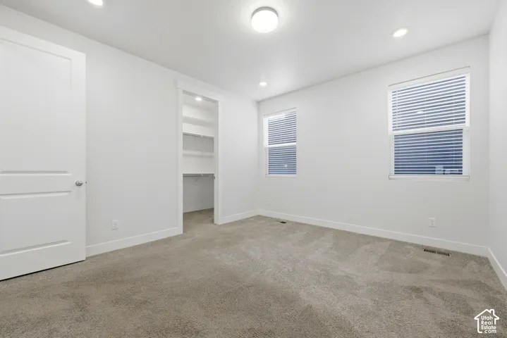 Recessed lighting, flush mount lighting, two windows with blinds, built-in closet shelving, and light-toned carpeting