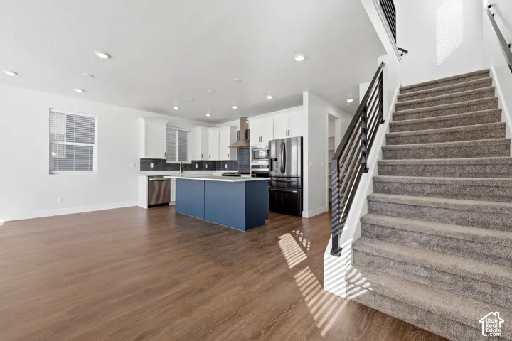 Open concept living space featuring wood-finish flooring, recessed lighting, and a modern kitchen with a blue-toned island