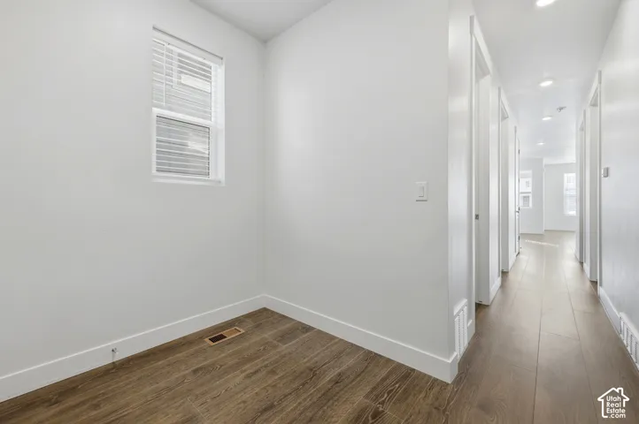 Wood-finish flooring throughout, white walls, and a recessed ceiling light in the hallway