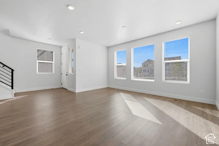 Wood-finish flooring, recessed ceiling lighting, multiple large windows, and a modern stair railing