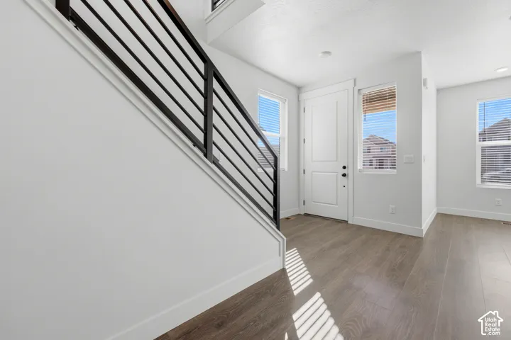 Entryway with wood-finish flooring, white walls, and a contemporary black metal staircase railing