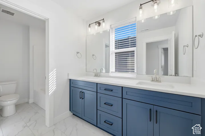 Dual vanity with a white countertop and integrated sinks, blue shaker-style cabinetry, and brushed nickel hardware