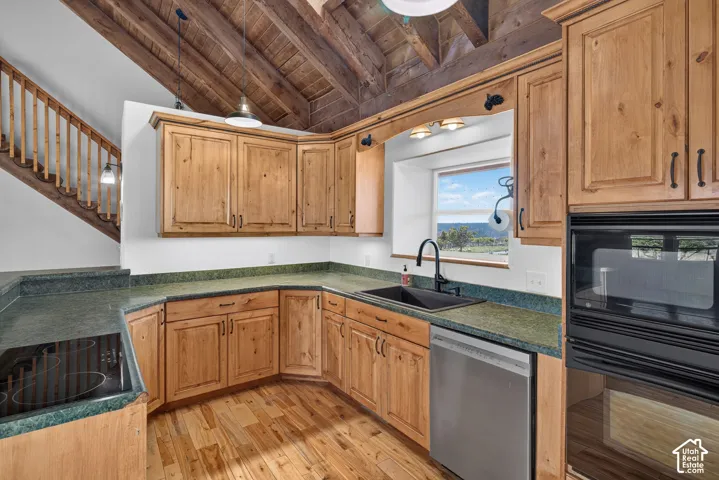Vaulted wood-plank ceiling, natural wood cabinetry, integrated stainless steel dishwasher, built-in wall oven and microwave, and wood-finish flooring