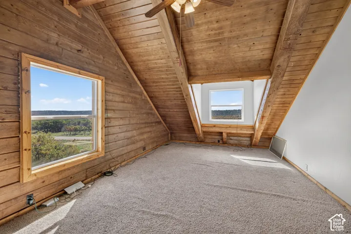 Wood-paneled sloped ceilings, exposed wooden beams, and multiple windows