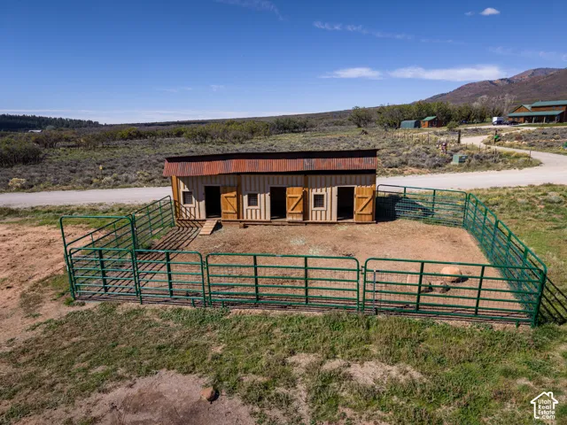 Rustic outbuilding with wood siding and a corrugated metal roof, surrounded by a metal fenced enclosure