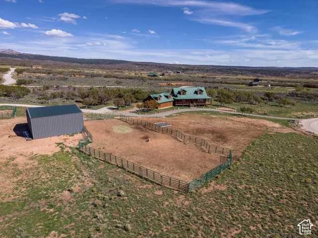Log home with a green roof, expansive fenced enclosure, and a gray utility shed