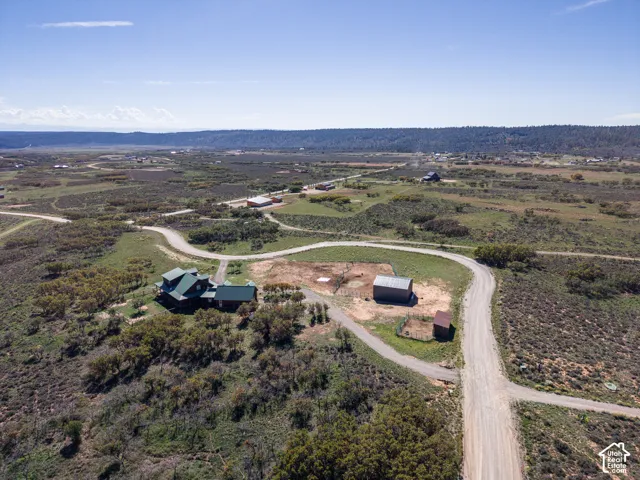 Expansive property featuring a residence with a green roof, two outbuildings, and natural landscaping