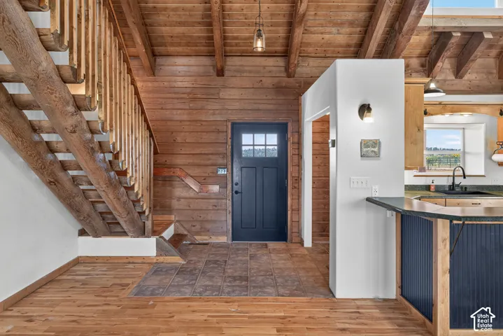 Exposed wood beam ceiling, wood-finish flooring, log staircase, and a solid door with windows