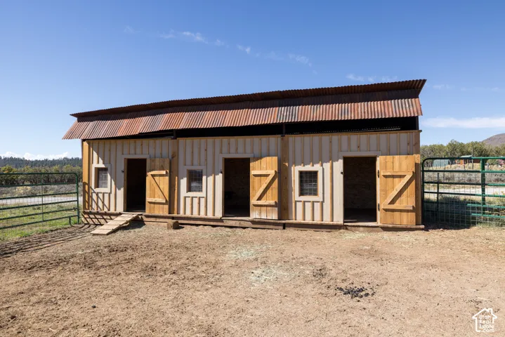Board-and-batten siding structure with a corrugated metal roof, multiple entryways, and two windows