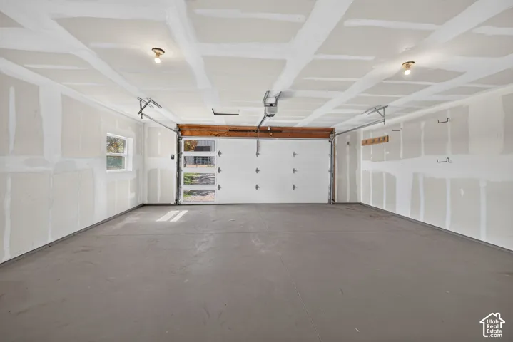 Spacious garage with an overhead door featuring frosted glass panels, a concrete floor, and overhead lighting