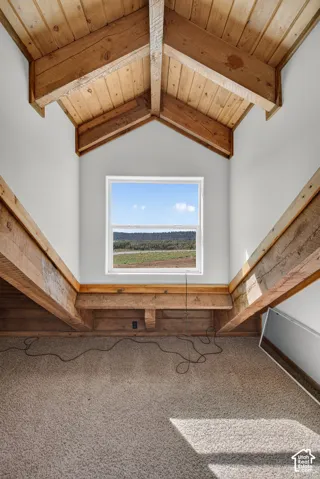 Pitched wood-plank ceiling with exposed beams, white painted walls, and a single window