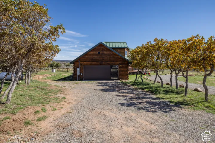 Detached garage structure with a green metal roof, wood siding, and a gravel driveway