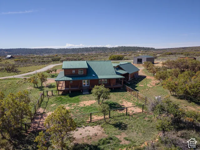 Wood-sided residence with green metal roofing, a covered porch, and a dedicated outbuilding