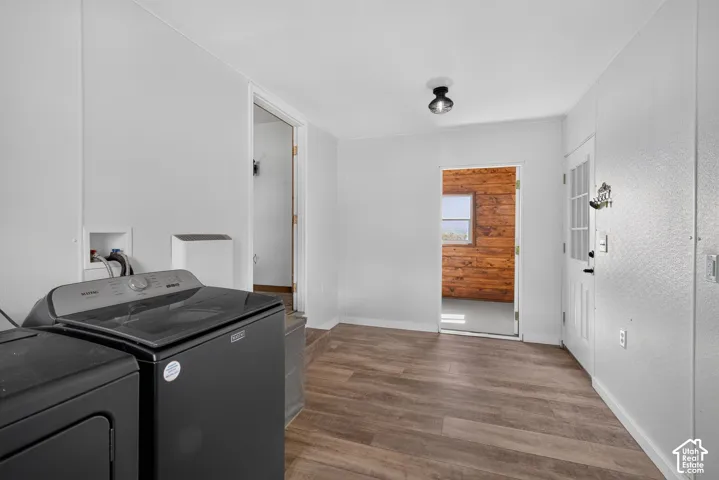 Laundry area with wood-finish flooring, white walls, and a recessed utility space