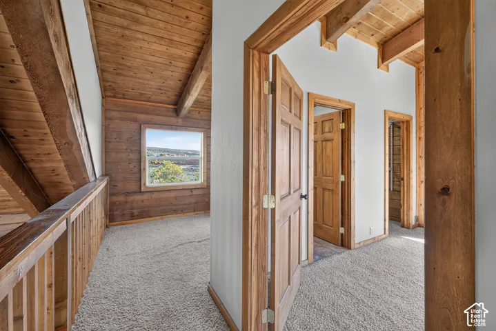 Exposed wood beam ceiling, wood-paneled walls, wood-finish doors, wood railing, and carpeted flooring