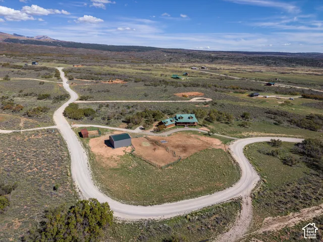 Aerial view showcasing a sprawling rural property with manicured grounds, mature tree clusters, and multiple outbuildings including barns and agricultural structures