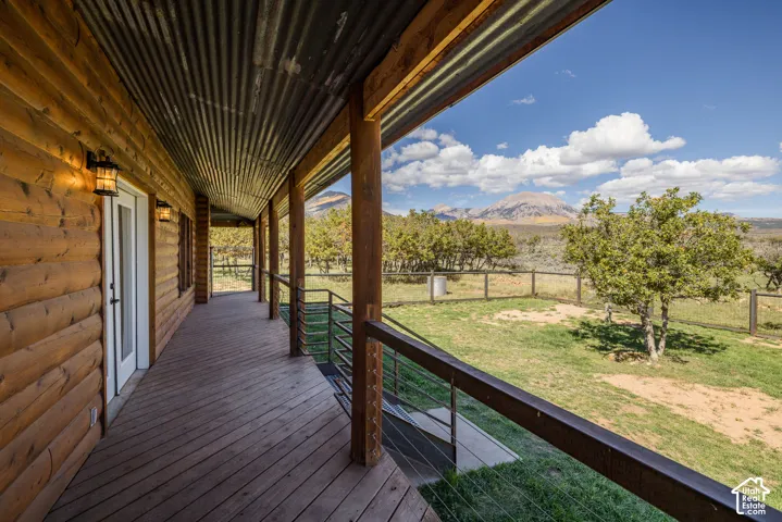 Expansive covered porch featuring a corrugated metal ceiling, wood plank flooring, and a log cabin exterior