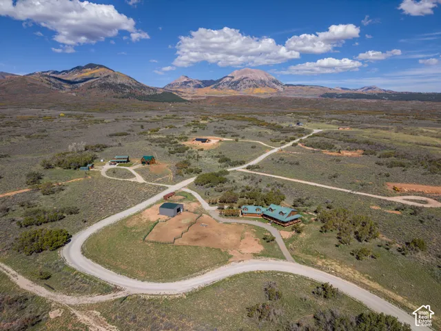 Expansive property featuring multiple structures, unpaved roadways, and mountainous backdrop