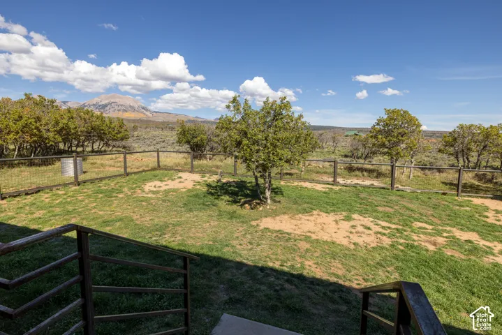 Fenced backyard with mature trees and mountain backdrop
