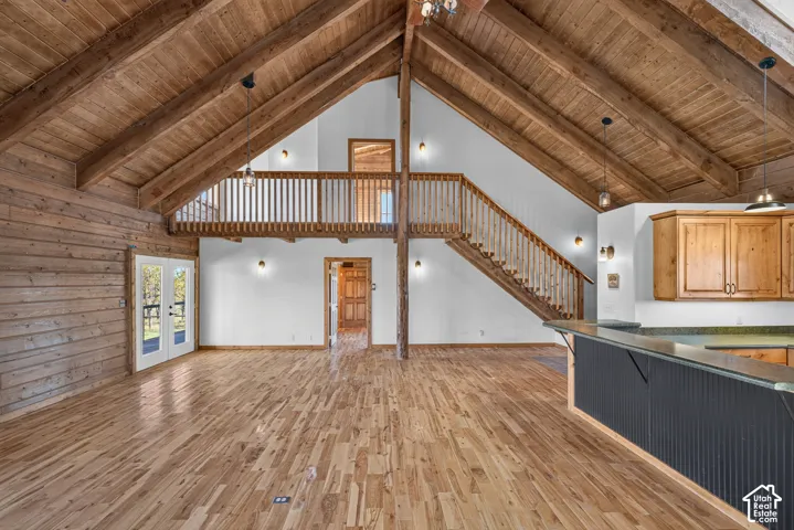 Open-concept living space showcasing exposed wood beam vaulted ceilings, wood-finish flooring throughout, and abundant recessed lighting
