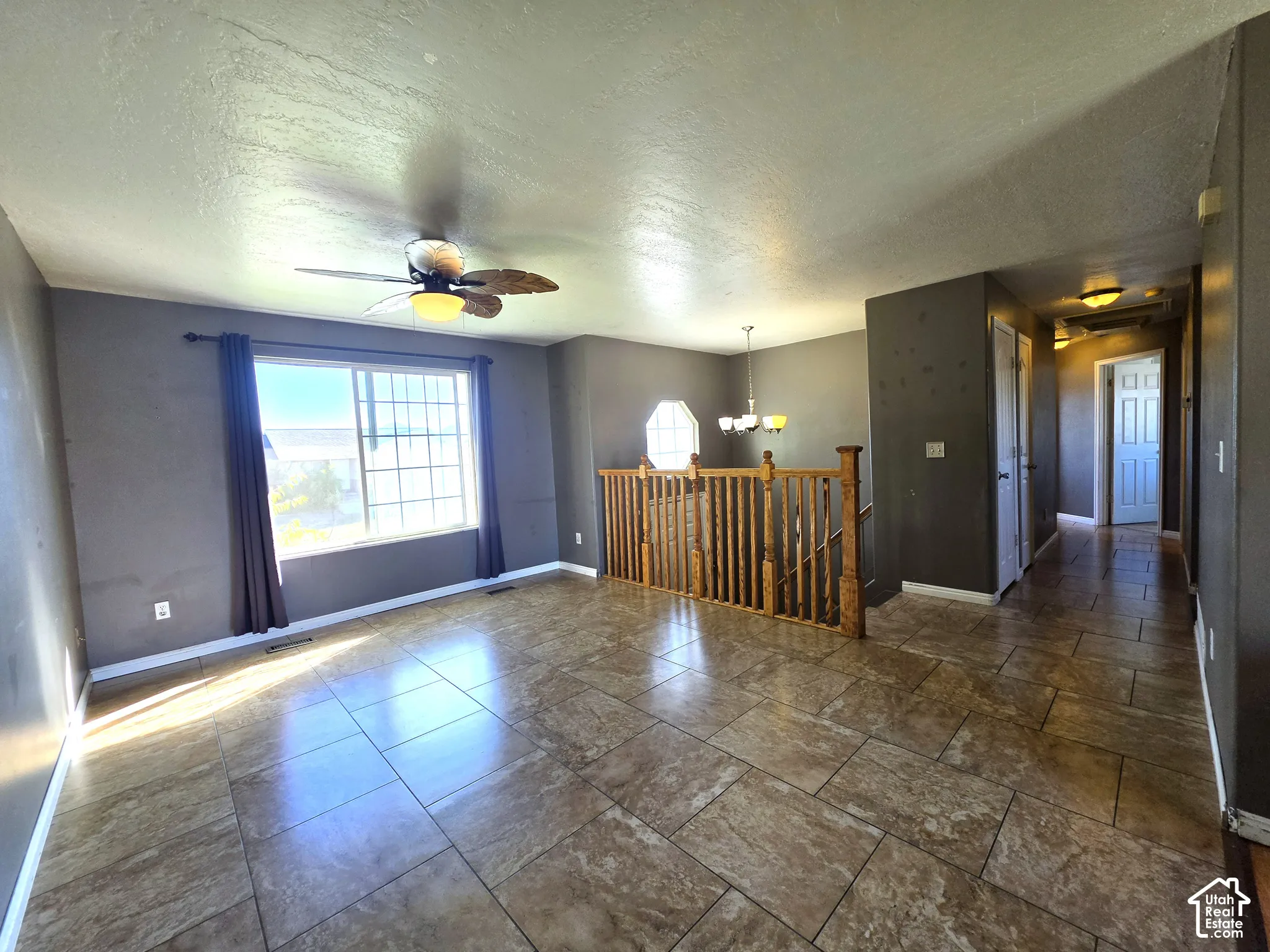 Spacious room with large windows, ceramic tile flooring, and a ceiling fan with integrated lighting