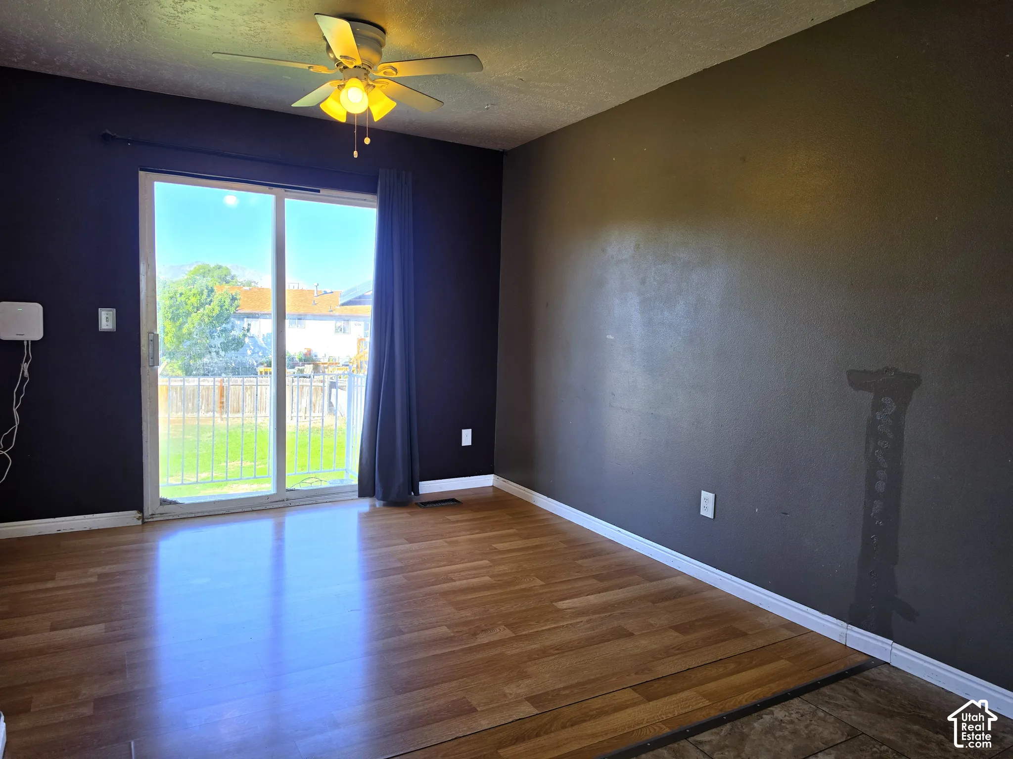 Wood-finish flooring, ceiling fan with integrated lighting, and sliding glass door