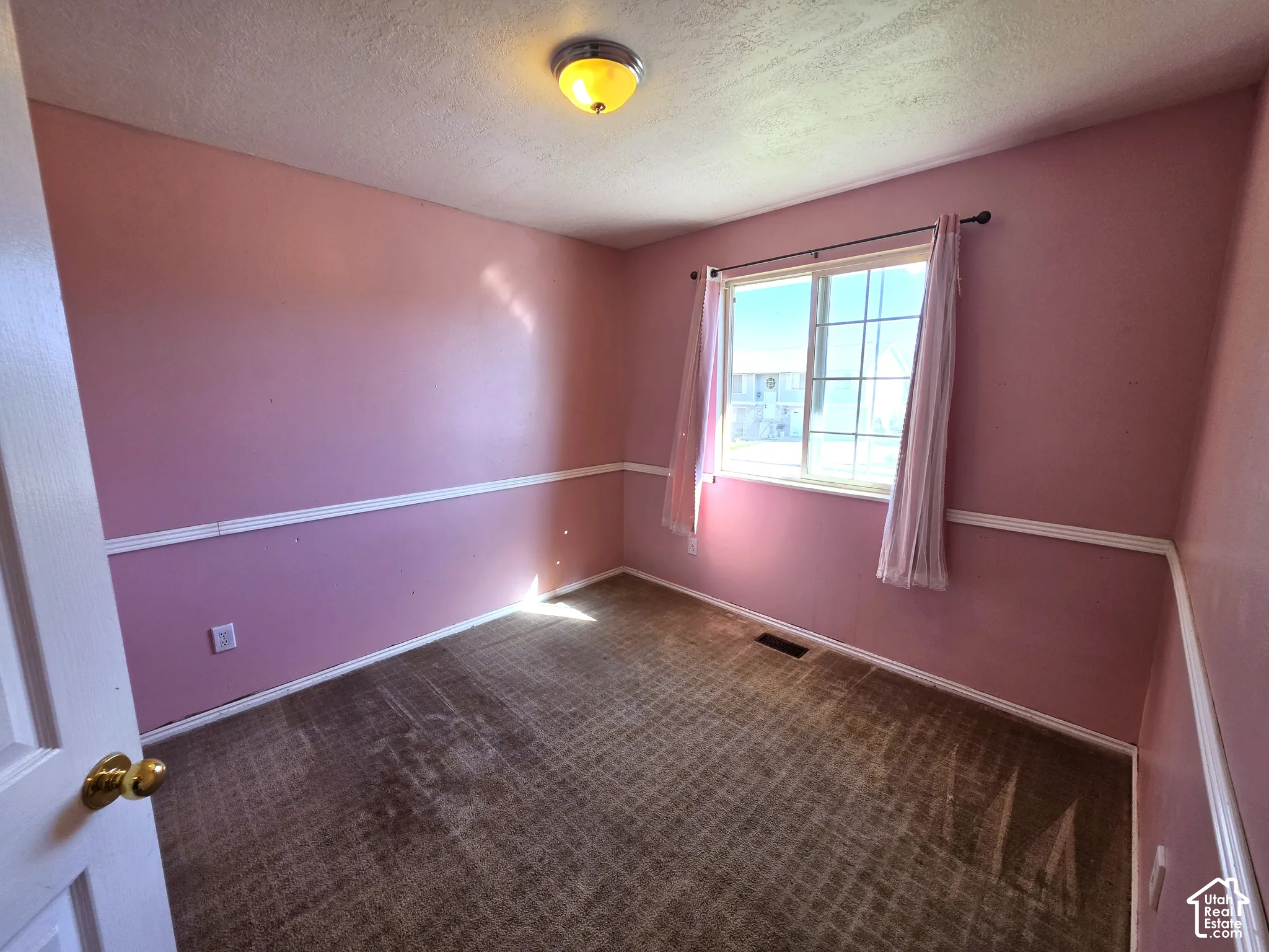 Wall-mounted light fixture, window with grid pattern, carpeted flooring, and white trim
