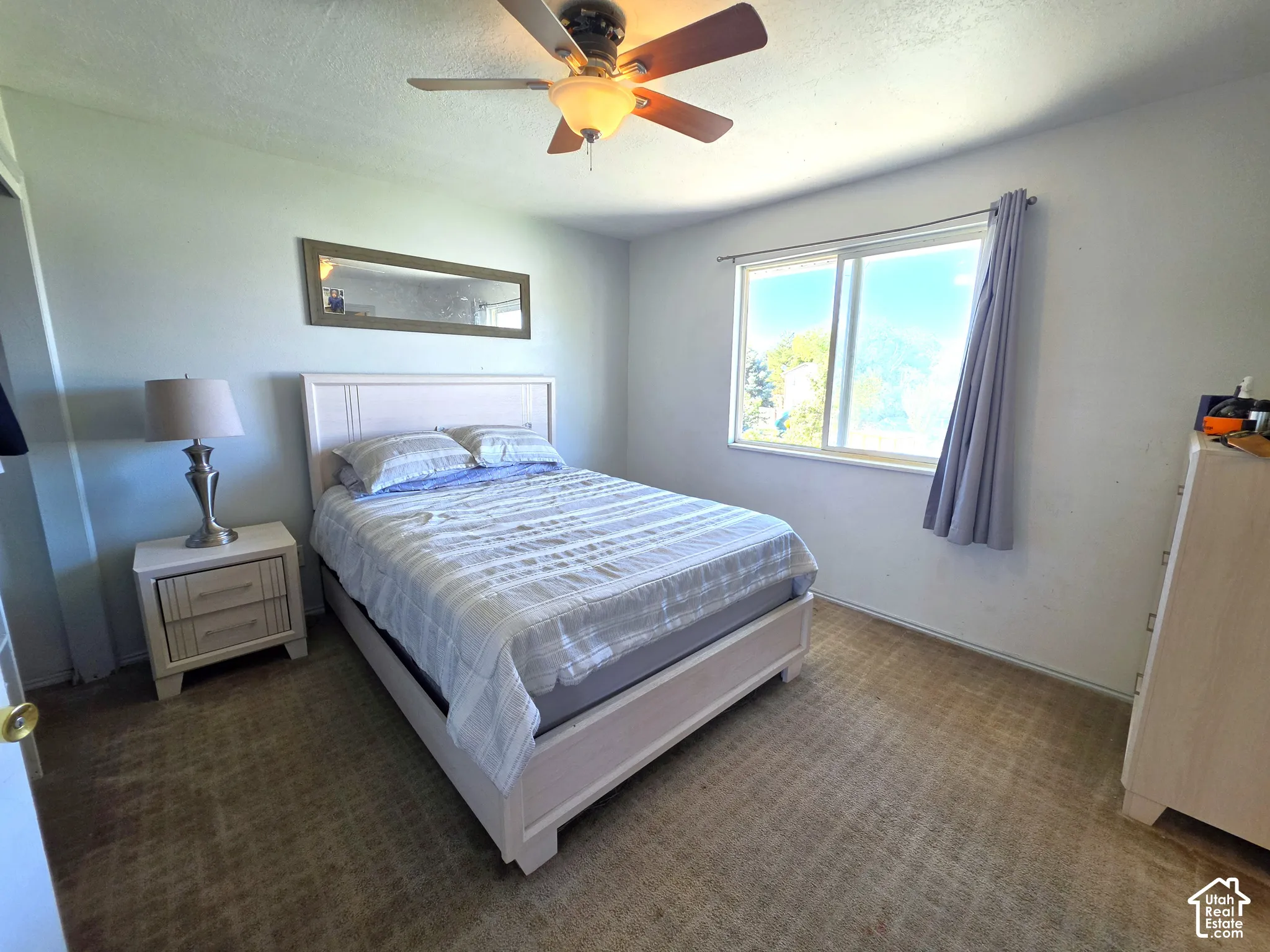 Room featuring a built-in ceiling fan with integrated lighting, a window with a curtain rod, and patterned carpeting