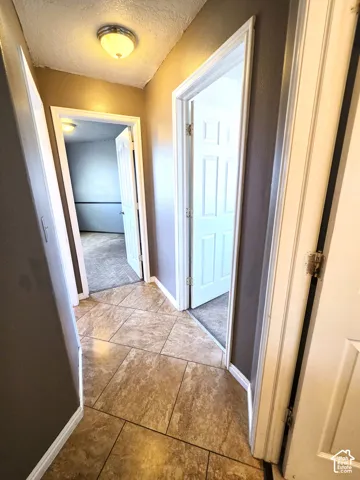 Hallway featuring rectangular tile flooring, semi-flush mount ceiling light, and interior paneled doors