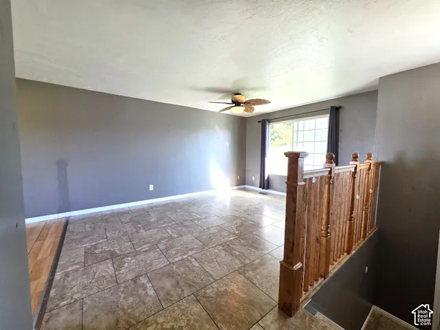 Spacious open-concept living area featuring polished concrete flooring, recessed lighting, and a ceiling fan