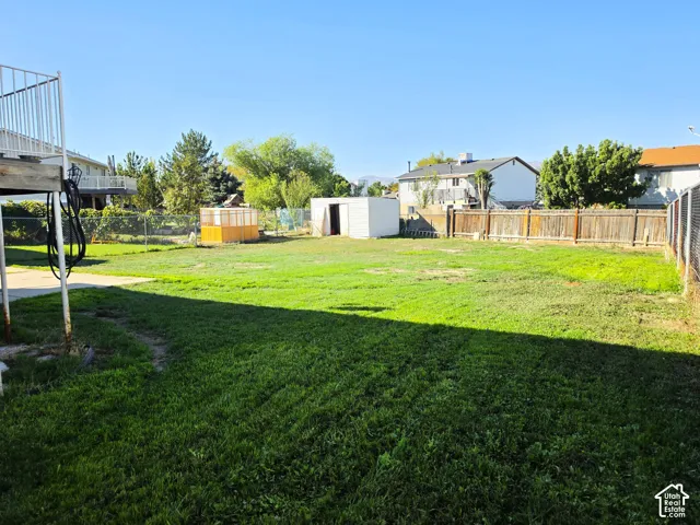 Expansive grassy yard with a white storage shed and a wood-panel fence